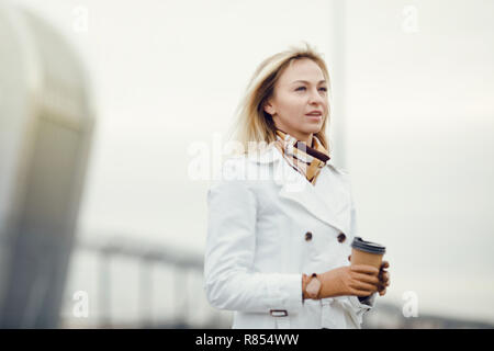 Young stylish pretty woman posing in the city streets and using  Stock Photo