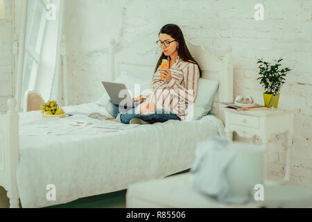 Working from home. The pregnant woman drinking a juice and working remotely Stock Photo