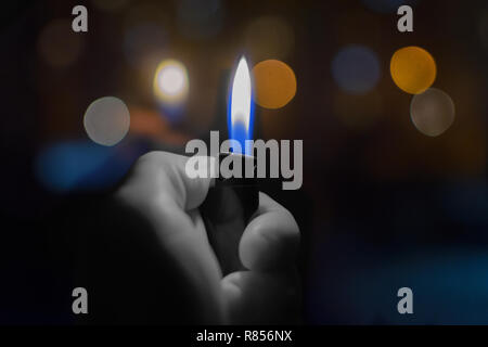 Lighter with fire in hand at the background of the night lights in the bokeh. Stock Photo