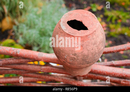 A broken clay pot of brown hanging upside down on a fence of wood Stock Photo