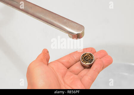 On the palm of the hand is a twisted water aerator with lime from the water. Stock Photo