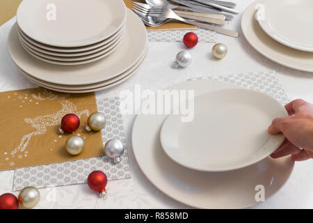 Woman hand puts a plate on Christmas Eve dinner Stock Photo
