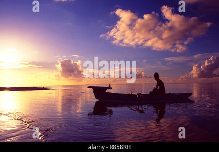 French Polynesia: Woman paddeling in a small boat at sunset at Bora Bora Island and Lagoon Resort Stock Photo