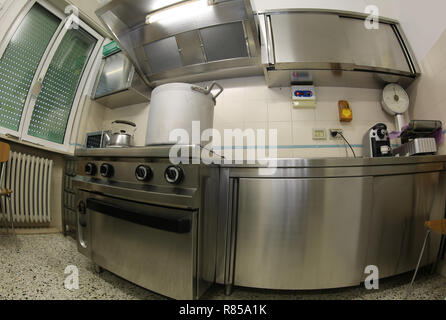 large industrial kitchen with steel stoves and a giant aluminum pot above the gas stove photographed by fisheye lens Stock Photo