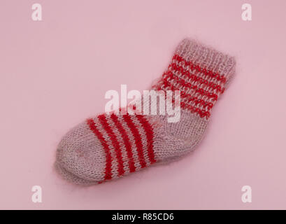 handmade woolen merino wool socks on pink rose background. craft store concept Stock Photo