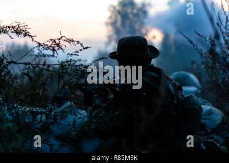 Sniper team armed with large caliber, sniper rifle, shooting enemy targets on range from shelter, sitting in ambush Stock Photo