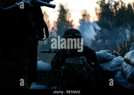 Sniper team armed with large caliber, sniper rifle, shooting enemy targets on range from shelter, sitting in ambush Stock Photo