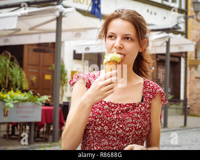 Young woman eating ice cream on a street, close up portrait Stock Photo