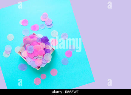 Top view of box full of colorful confetti on pastel blue and violet background with copyspace. Stock Photo