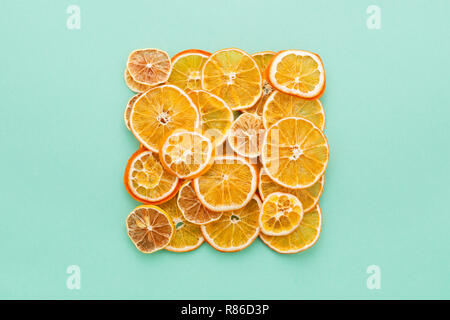 Dried citrus slices lemons & oranges on turquoise colored background. Homemade Christmas natural decoration. Square shape, Flat Lay. Stock Photo