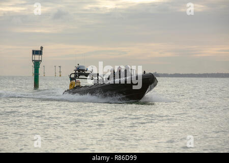Police rib moving at speed across Portsmouth harbour. Three uniformed officers on board. High security for the royal dockyard during event. Stock Photo