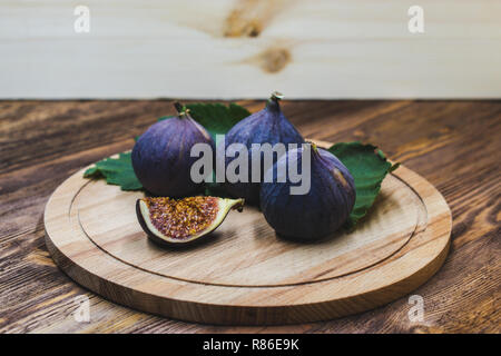 A few vivid cuted figs on a plate on an old wooden background Stock Photo