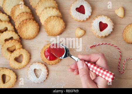 Top view of traditional Christmas Linzer cookies filled with strawberry jam on wooden board. These are traditional Austrian filled biscuits. Stock Photo