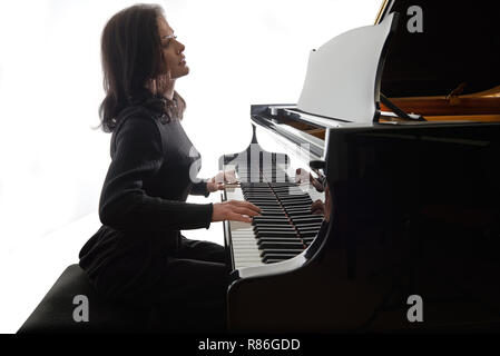 Young musician plays the grand piano, silhouette image isolated on white background Stock Photo