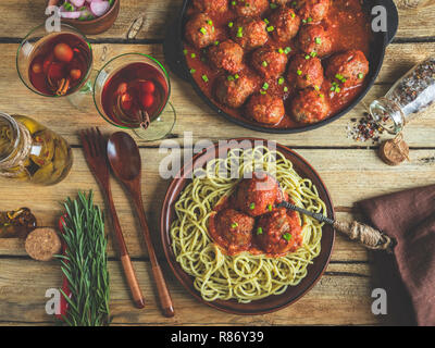 Homemade meatballs in tomato sauce with pasta on a plate. Frying pan on a wooden surface Stock Photo