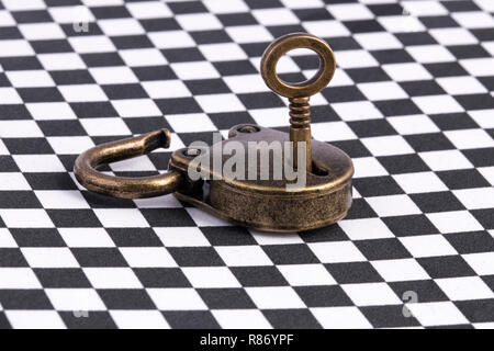 open bronze key lock on a checkerboard surface, background image Stock Photo