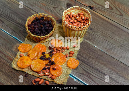 peeled raw peanuts dried apricots raisins on a wooden table background close-up Stock Photo