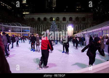 Citi Pond ice skating rink at Bryant Park in Manhattan with Christmas Tree on display. People ice skating at the rink at Bryant Park in New York City. Stock Photo