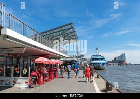 Cafes and boats moored along the St. Pauli Landungsbrücken (St Pauli Piers), Hamburg, Germany Stock Photo