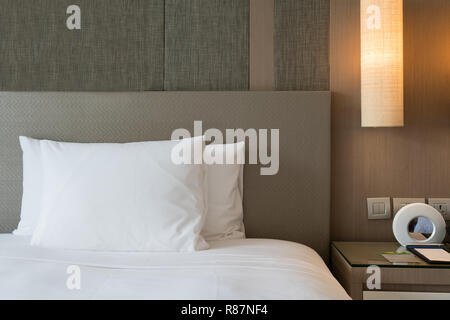 Close up fragment of bedroom with reading lamp and digital alarm clock in modern home or hotel. Stock Photo