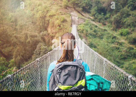 Rear view of girl with backpack crossing the suspension bridge Stock Photo