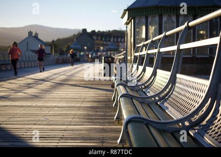 Young joggers get exercise on Bangor Pier at dawn, Bangor, Gwynedd, North Wales, UK Stock Photo