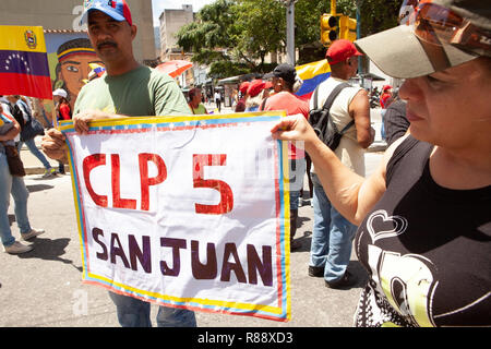 Venezuelans marching in city carrying CLP San Juan poster and Venezuelan flag, Caracas, Venezuela, South America Stock Photo