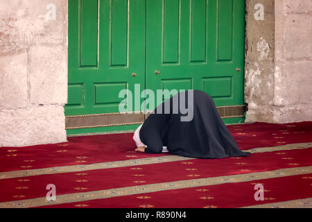 Young praying woman falling on knees against mosque Dome of the Rock in the Muslim quarter of the old city of Jerusalem in Israel Stock Photo