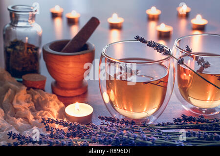 Herbal teain a glass cups with lavender on a kitchen table with candle lights Stock Photo