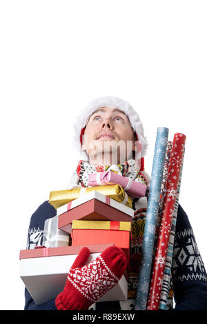 Photo of pensive man in Santa's cap with boxes with gifts, wrapping paper in hands Stock Photo