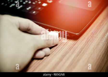 hand plugging usb cable in notebook device / white electronics cable in usb port on computer accessories Stock Photo