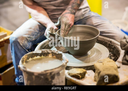 Potter man working on clay bowl. Pottery production process in close-up Stock Photo