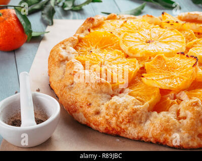 Close up view of caraway and orange tart on backing paper over black cement background. Winter season and christmas ideas recipe - tart with caraway pastry and oranges, mandarines or tangerines. Stock Photo