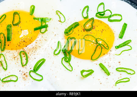 close up of homemade scrambled eggs from two eggs with green onions in a pan Stock Photo