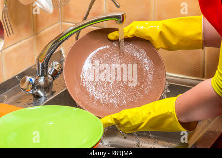 close-up of hands with plates in gloves - homework washing dishes Stock Photo