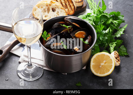 Mussels in copper pot and white wine on stone table Stock Photo