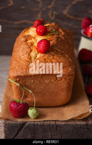 Strawberry yogurt fluffy pound cake with fresh berries on a parchment paper on a wooden board. Stock Photo