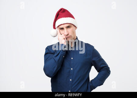 Portrait of sad man in red santa claus hat. Stock Photo