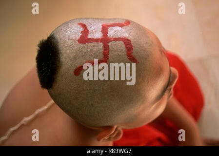 Red swastik symbol on bald head Indian boy mundan thread ceremony India Stock Photo