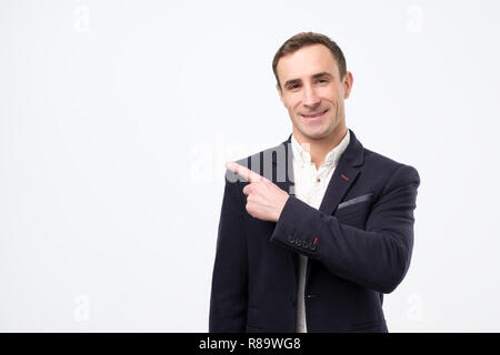 Successful stock market broker guy with suit smiling, is pointing on a copyspace with his finger Stock Photo