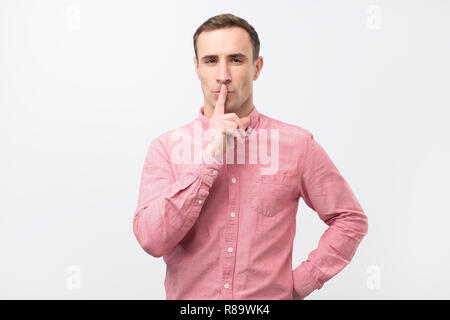 Italian young man in pink shirt doing a silence gesture Stock Photo