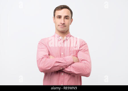 Smiling young man standing with arms crossed against gray background Stock Photo