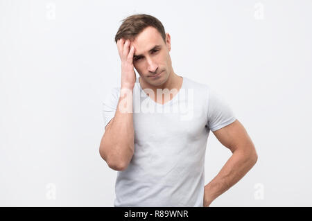 Serious italian male has attentive look, keeps hand on head, looking down. Stock Photo