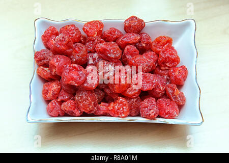 Prunes in a square white bowl on a white background. Prunes are the dried fruit group . Raisin in the bowl on the wood background Stock Photo