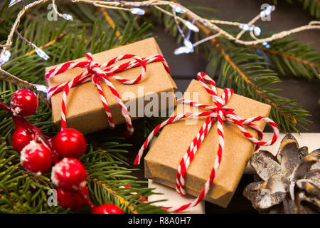 Two wrapped in craft paper presents on natural fir tree with christmas decorations, soft focus Stock Photo