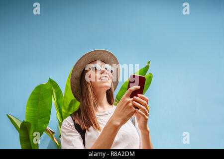 Excited young female on vacation uses smartphone Stock Photo