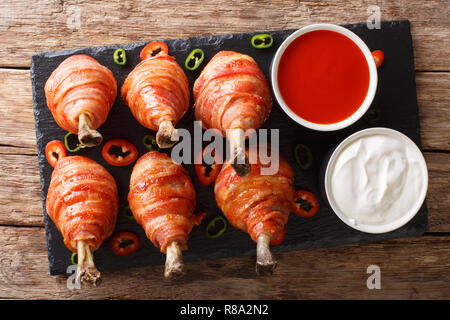 Bacon Wrapped Chicken Lollipops with sauces close-up on the table. horizontal top view from above Stock Photo