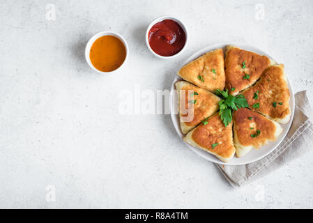 Deep fried vegetable pies with sauces, samsa, samosas, echpochmak - traditional meat stuffed pies or vegetarian pies on white background, copy space. Stock Photo