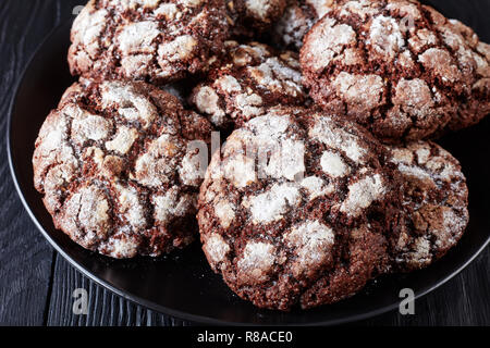 close-up of Chocolate Crinkle cookies. Cracked chocolate biscuits. Chocolate biscuits, Christmas cookies on a black plate on a black wooden table, vie Stock Photo