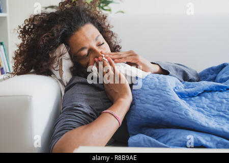 Sick black woman at home blowing her nose